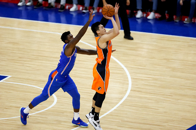 NBA 比赛现场,球员在三分线外起跳投篮,防守球员紧随其后